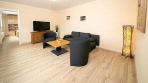A living room with a sofa set, a coffee table, a TV, and a lamp. - Apartment on a Farm Near Dusseldorf (Juechen)