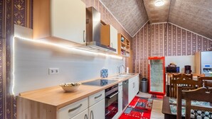 Cozinha compacta com bancada de madeira, armários brancos e tapete vermelho estampado.