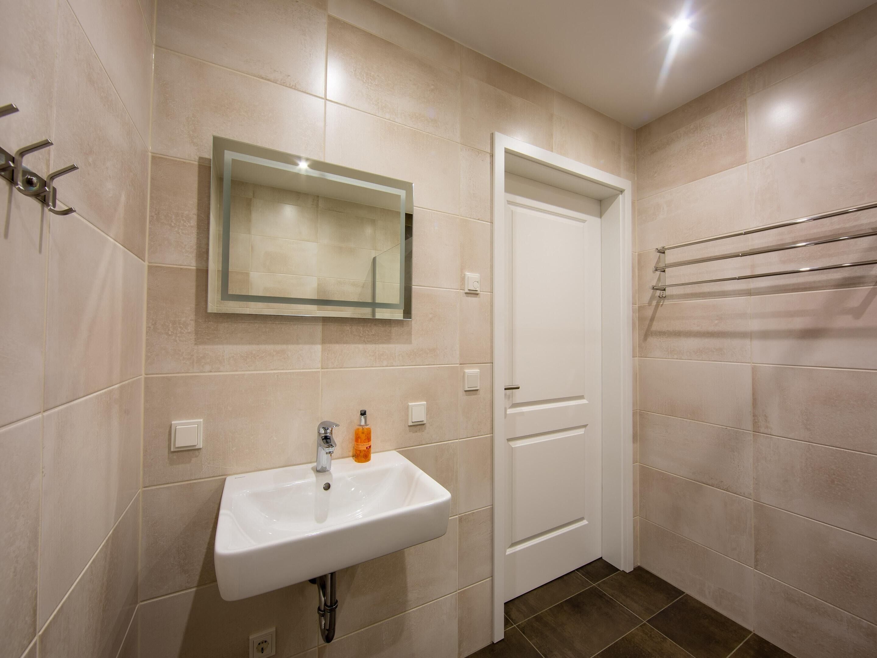A bathroom with a white sink, a mirror, and a towel rack.