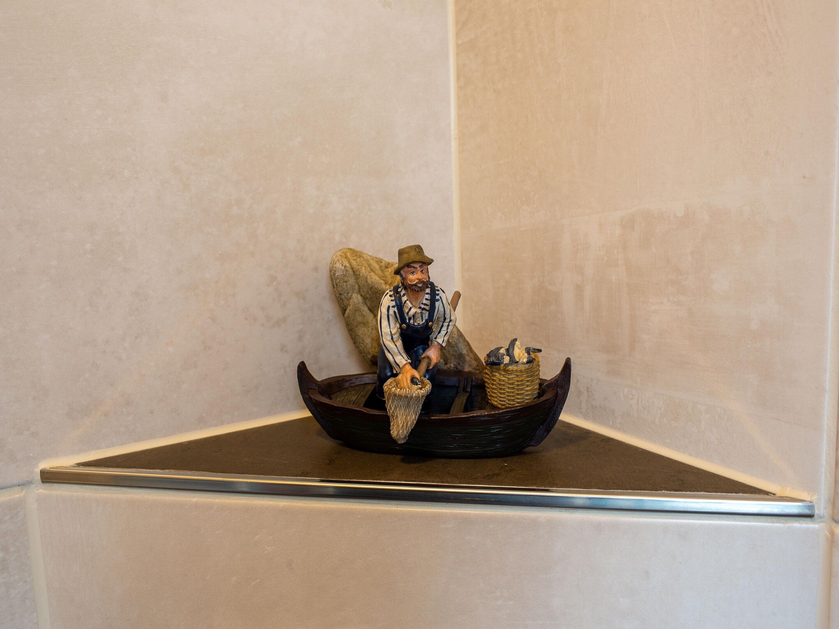 A figurine of a man in a boat with a basket, placed on a display stand.