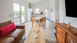 A modern living room with a sofa, a wooden coffee table, and a dining area with chairs and a table. - Ferienwohnung Eifelruhe in Filz (Filz)