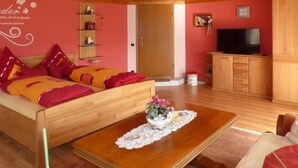 Ein gemütliches Zimmer mit einem hölzernen Bett, einem Fernseher und einer kleinen Kommode.