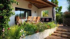 A patio with a table and chairs, surrounded by a garden with various plants and flowers. - Villa Maestro Maria 🏡Warm welcome 🧡 heated pool 🌞beach 5' away 🏖️ (Lecci)