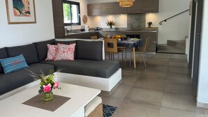 A modern living room with a sofa, coffee table, and a dining area with chairs and a table. - Villa Maestro Maria 🏡Warm welcome 🧡 heated pool 🌞beach 5' away 🏖️ (Lecci)