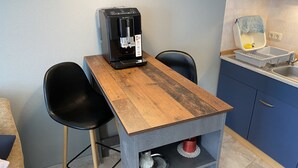 Eine kleine Küche mit Kaffeemaschine, zwei Stühlen, einem Spülbecken und einer kleinen Ablagefläche.