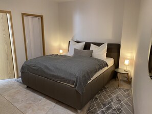 A neatly made bed with a striped blanket, two bedside lamps, and a small bedside table.