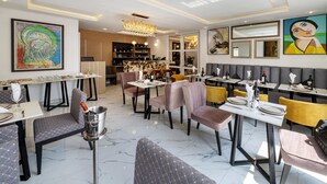 Un comedor moderno con suelo de mármol, mobiliario contemporáneo y obras de arte en las paredes.