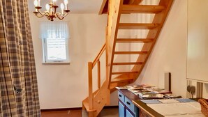 A staircase leading to an upper floor, a window with a view, a chandelier, and a desk with books and papers. - Holiday Home With Natural Garden (Kaltennordheim)