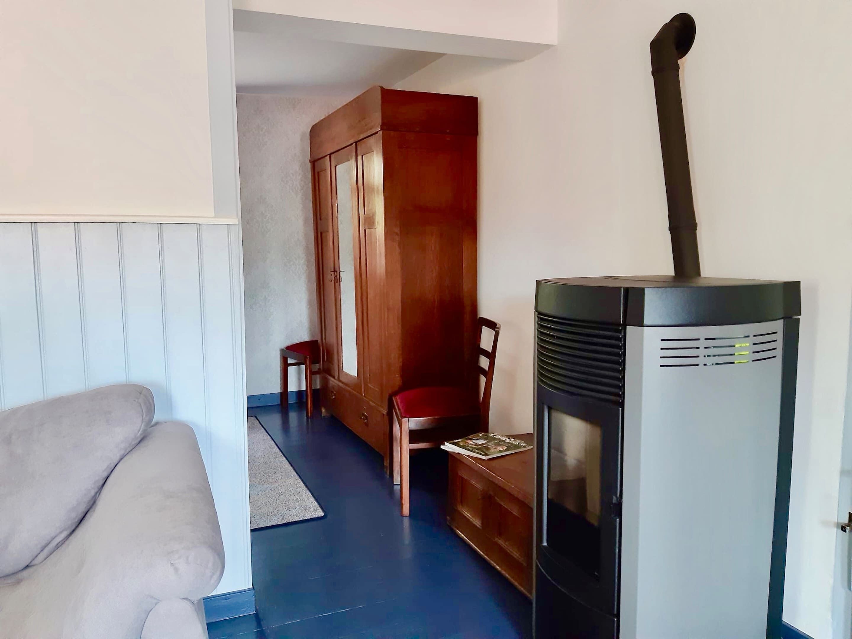 Una habitación con sofá, armario de madera y calefactor negro.