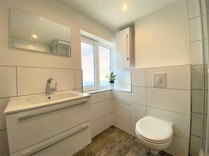 A modern bathroom with a white sink, mirror, and toilet. - Ferienwohnung Am Marktplatz in Herbolzheim (Herbolzheim)