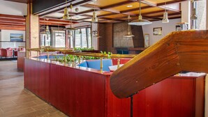 Un bar moderno con asientos rojos, lámparas colgantes y un diseño de listones de madera en el techo.