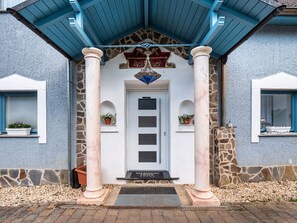 A building with a white door, stone columns, and a blue roof.