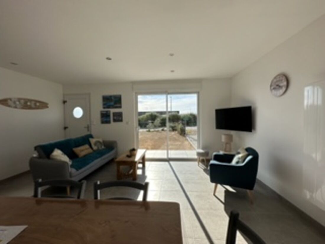 Uma sala de estar moderna com um sofá, televisão e área de jantar.