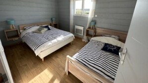 Une chambre avec deux lits, des têtes de lit en bois, des tables de chevet et une fenêtre avec des rideaux.