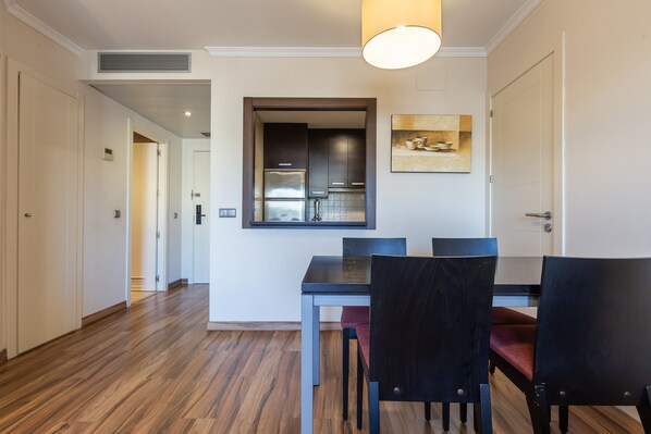 A modern kitchen with stainless steel appliances, a dining area with a table and chairs, and a hallway leading to another room.