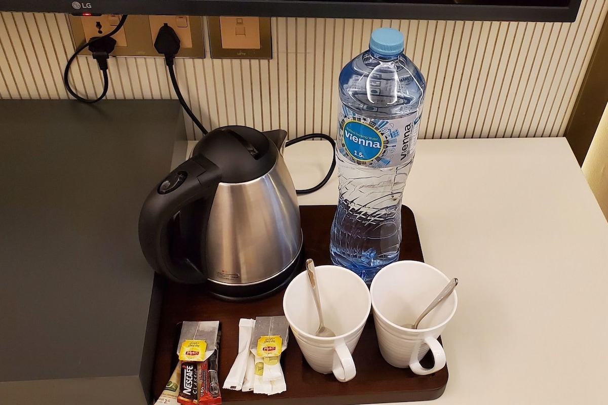 A kitchen counter with a kettle, water bottle, cups, and tea packets.