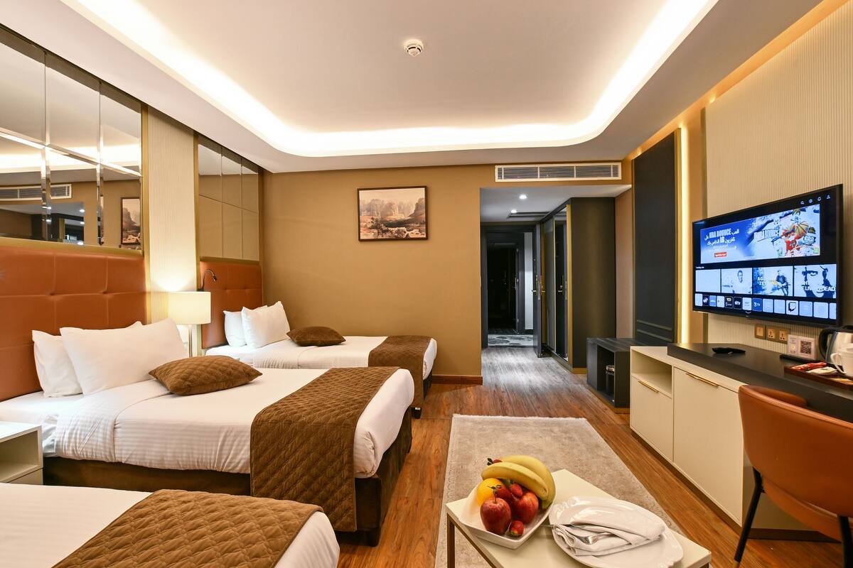 Habitación de hotel con dos camas, un escritorio, un televisor y un frutero.
