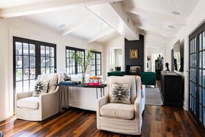 Amplia sala de estar con dos sillones blancos, una mesita de centro y una chimenea.