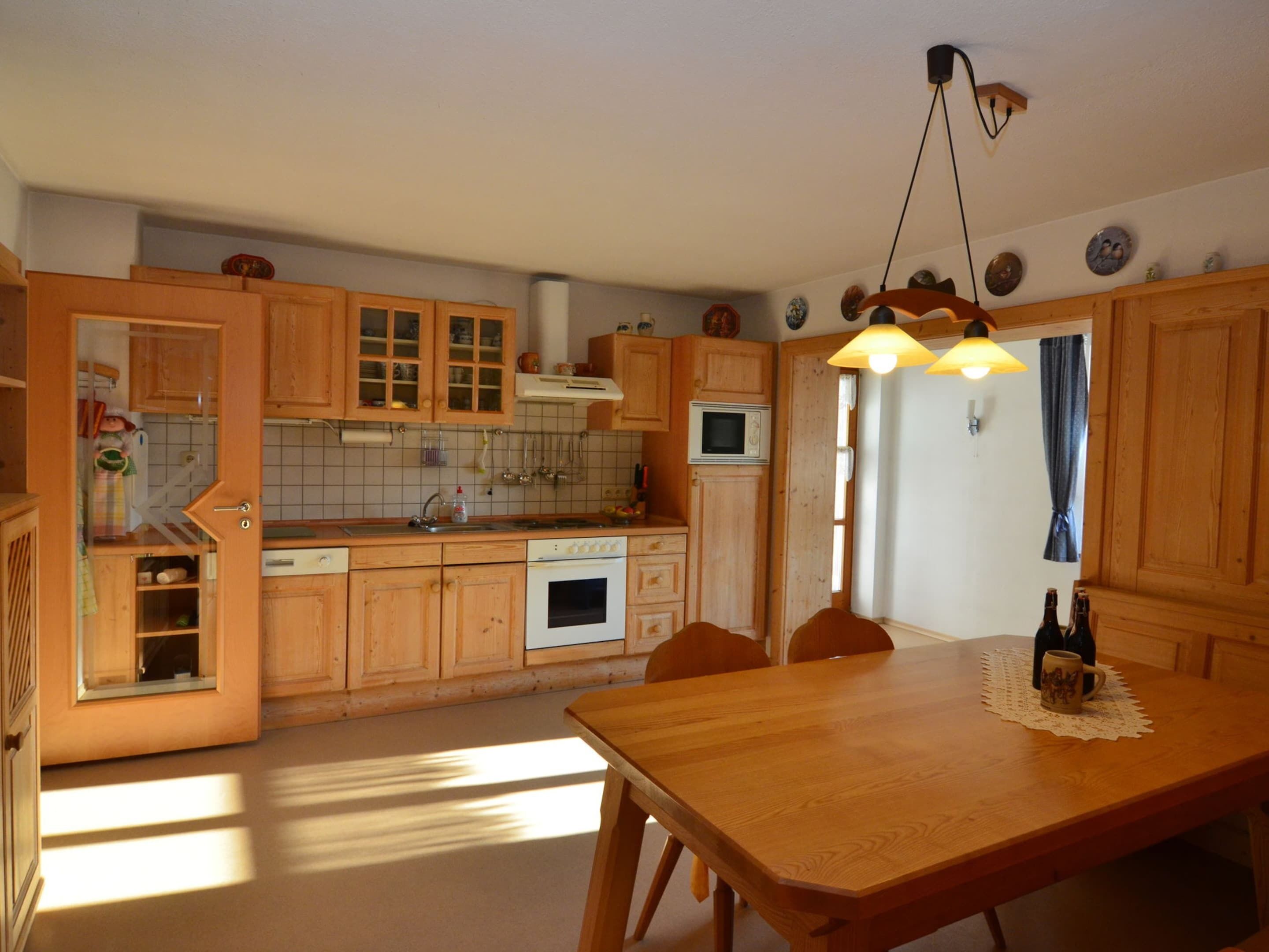 Cucina con mobili in legno, un tavolo da pranzo e una lampada a sospensione.