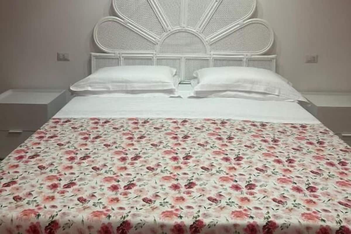 A bed with a white headboard and floral bedspread.