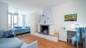 A modern living room with a sofa, a desk, and a fireplace. - Almare' (Crotone)