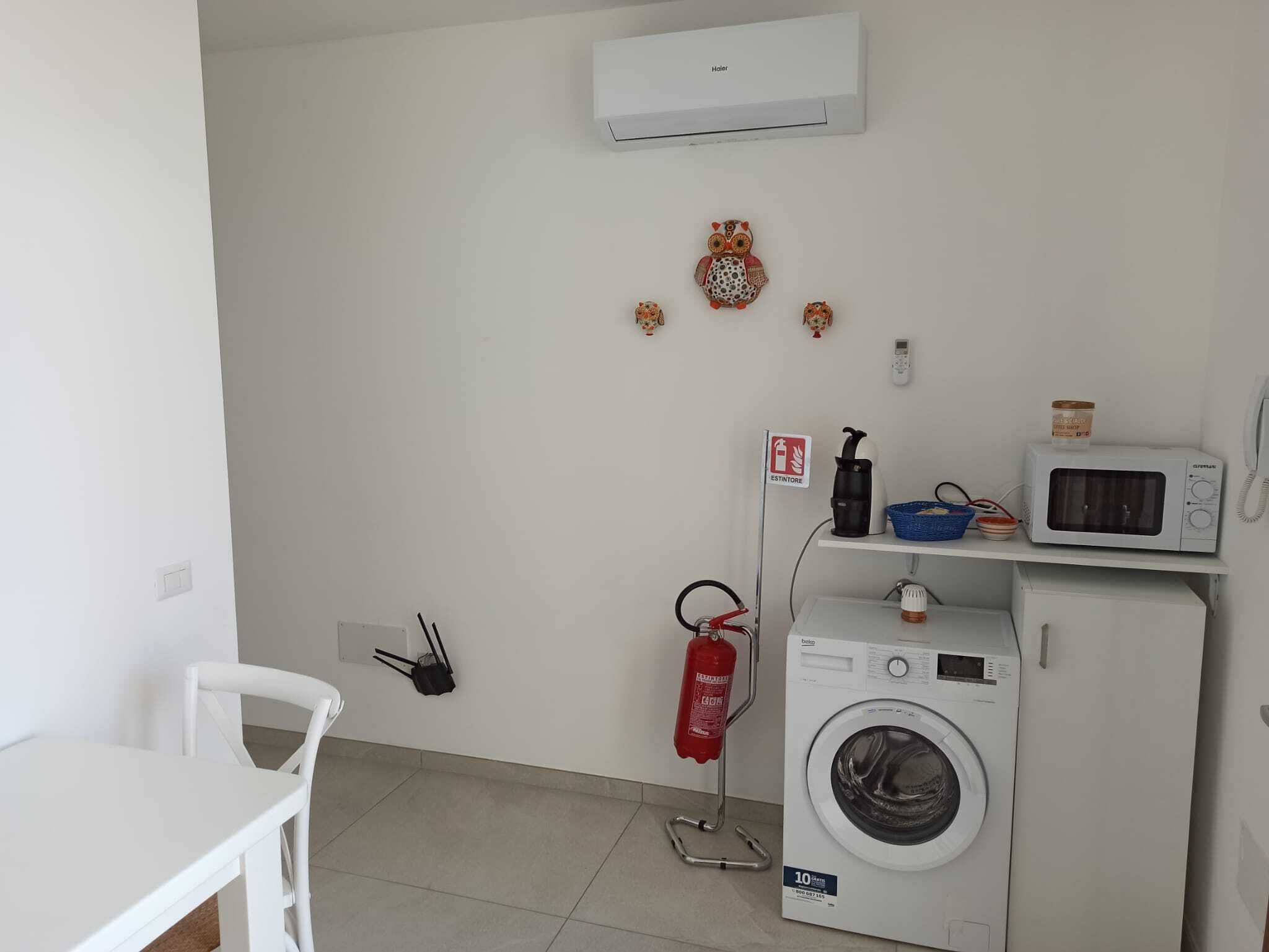 A laundry room with a washing machine, a microwave, and a fire extinguisher.