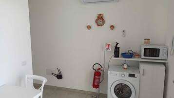 A laundry room with a washing machine, a microwave, and a fire extinguisher.