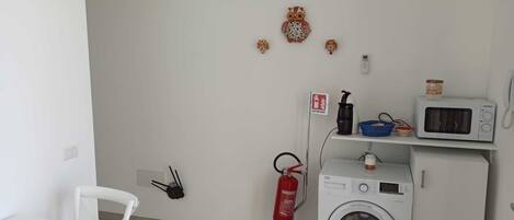 A laundry room with a washing machine, a microwave, and a fire extinguisher.