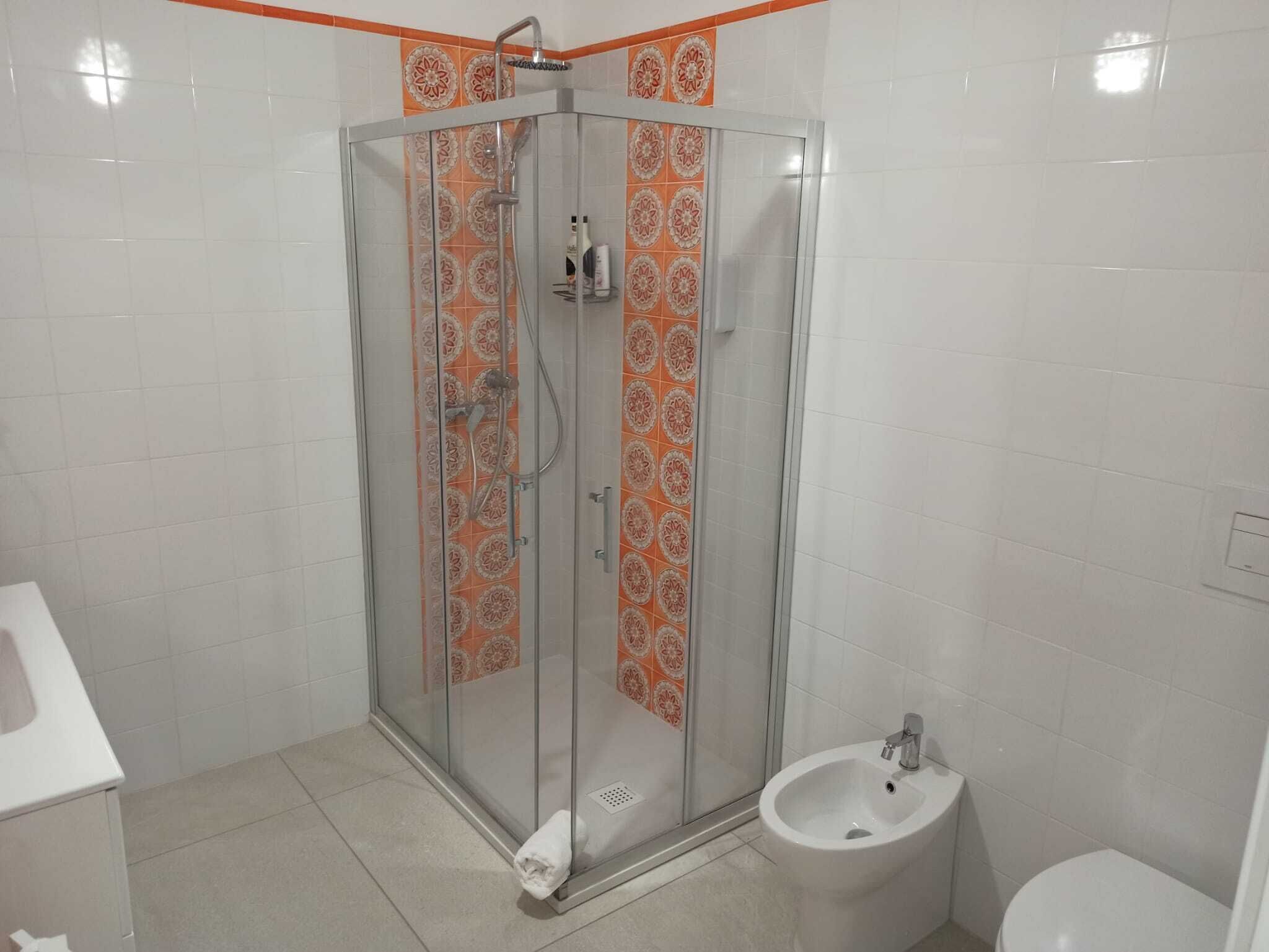 A bathroom with a glass-enclosed shower, a bidet, and a white sink.