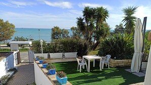 A patio with a white table and chairs, surrounded by potted plants and a view of the sea. - Almare' (Crotone)