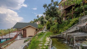 Ein Hotel an einem Hang mit Pool, einem Gartenweg und einem Wasserfall.