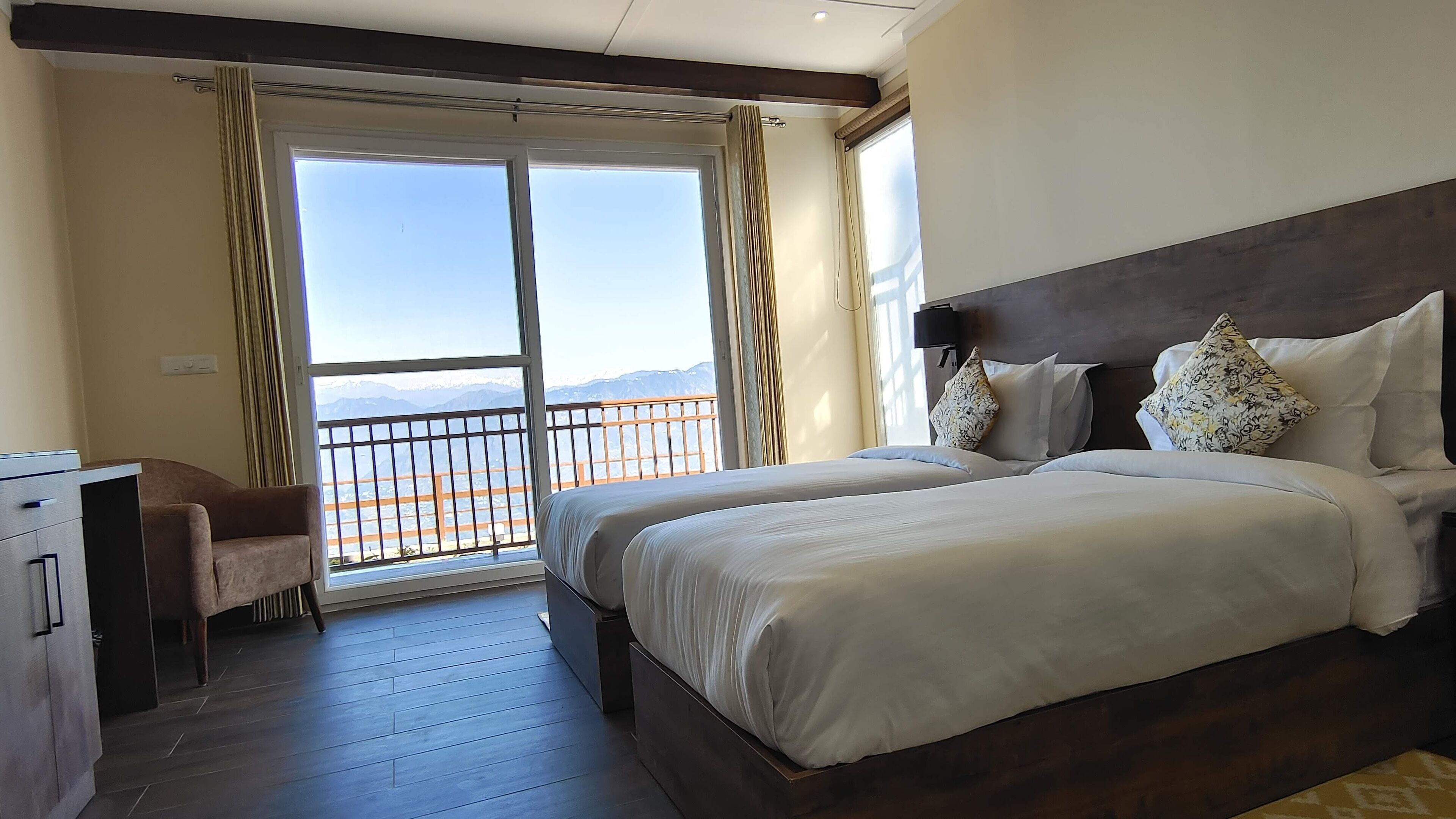 Habitación de hotel con una cama grande, un escritorio y un balcón con vistas a la montaña.