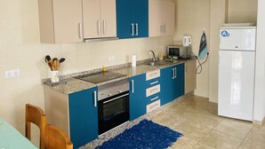 Uma cozinha moderna com armários azul e bege, forno embutido, micro-ondas e geladeira branca.