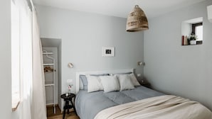 A bedroom with a bed, bedside table, and a hanging light fixture.
