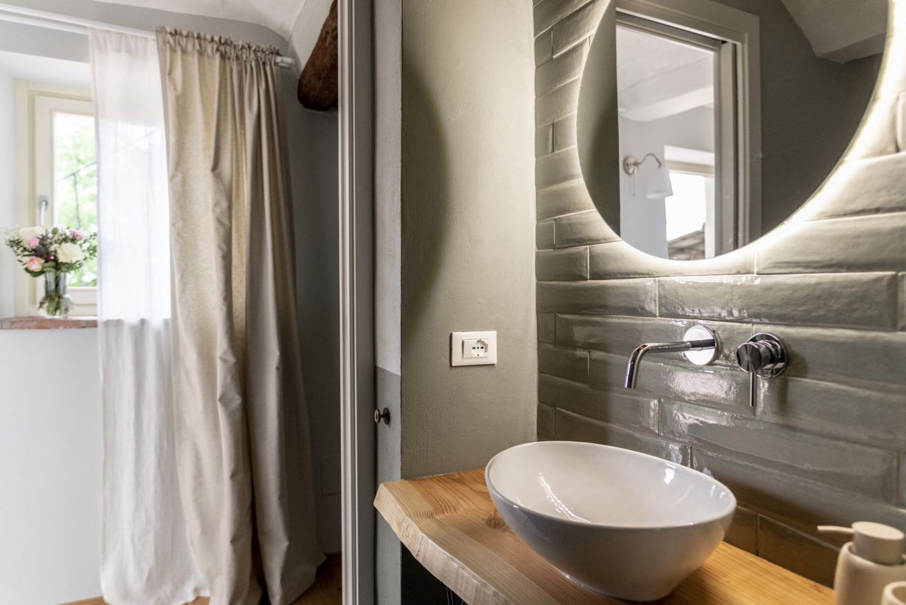 Un baño con un lavabo blanco grande, un espejo curvo y una cortina de ducha.