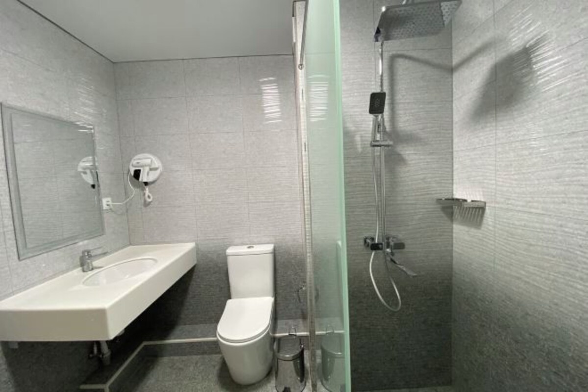 A modern bathroom with a glass-enclosed shower, a white sink, and a toilet.
