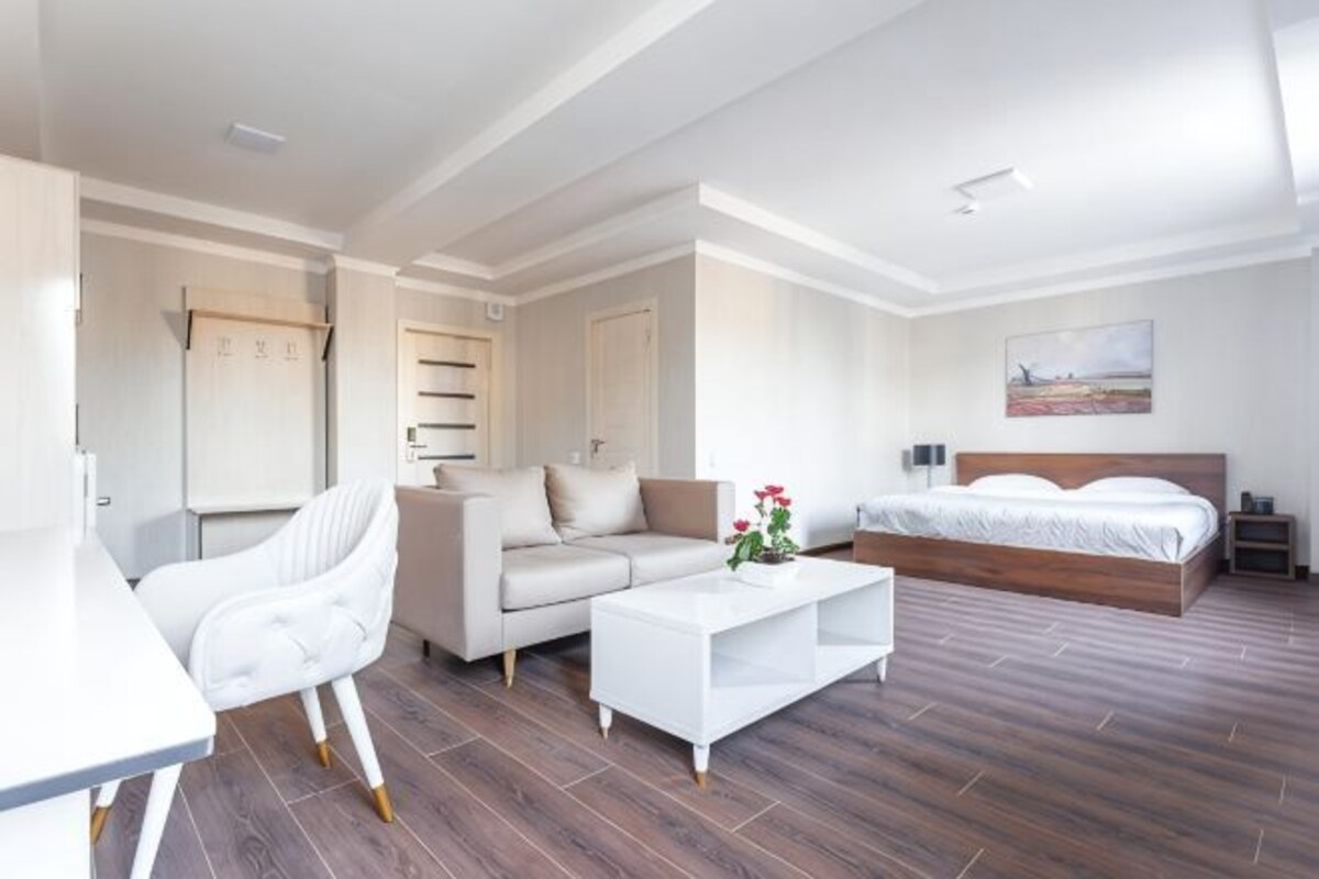A modern hotel room with a sofa, a bed, a desk, and a coffee table.