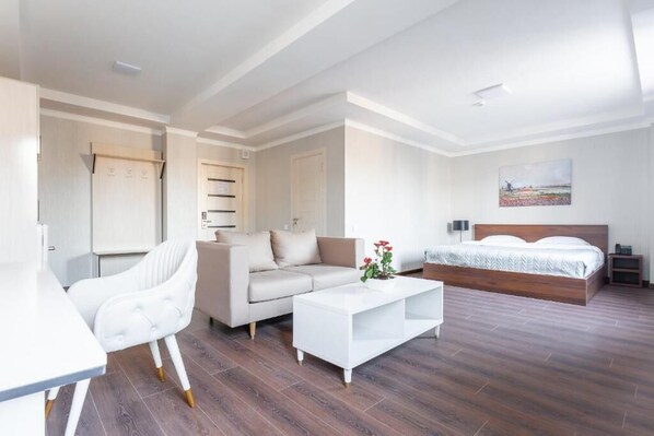 Una habitación de hotel moderna con cama, sofá, mesa de comedor y una silla.