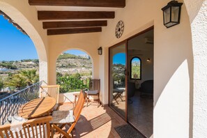 A balcony with a wooden table and chairs, a clock, and a view of the landscape. - CostaBlancaDreams - Casa Narciso in Calpe (Calpe)
