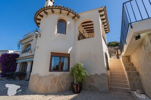 A building with a stone facade, a balcony with a metal railing, and a staircase leading to an upper level. - CostaBlancaDreams - Casa Narciso in Calpe (Calpe)