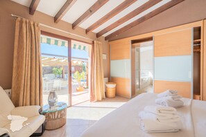 A hotel room with a bed, a sofa, a glass-top table, and a view of the outside. - CostaBlancaDreams - Casa Narciso in Calpe (Calpe)
