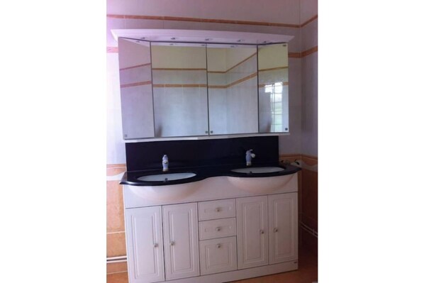 A bathroom with a double sink vanity, a large mirror, and a cabinet with drawers. - Manoir des Ullis (Saint-Pierre-en-Auge)