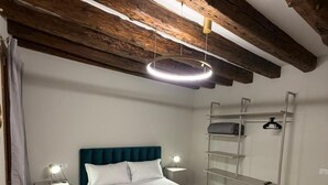 Un dormitorio con cama, mesitas de noche, un espejo y una lámpara colgante.