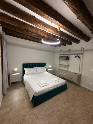 Un dormitorio con cama, mesitas de noche, un espejo y una lámpara colgante.