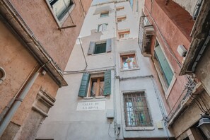 A narrow street with buildings featuring traditional architecture, including a sign reading "Calle de la Bissa." - Rialto Suite (Venice)