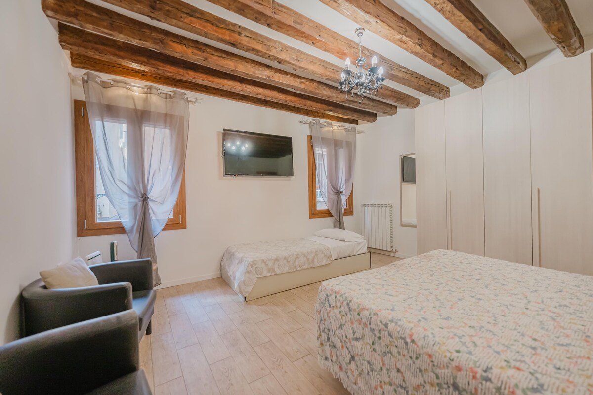 A bedroom with a large bed, a smaller bed, a TV, and a wardrobe.