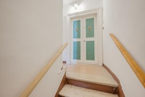 A staircase with wooden handrails leading to a door with green glass panels and brass handles. - Rialto Suite (Venice)