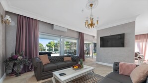 Una sala de estar moderna con un sofá gris, una mesa de centro con frutas y un televisor montado en la pared.