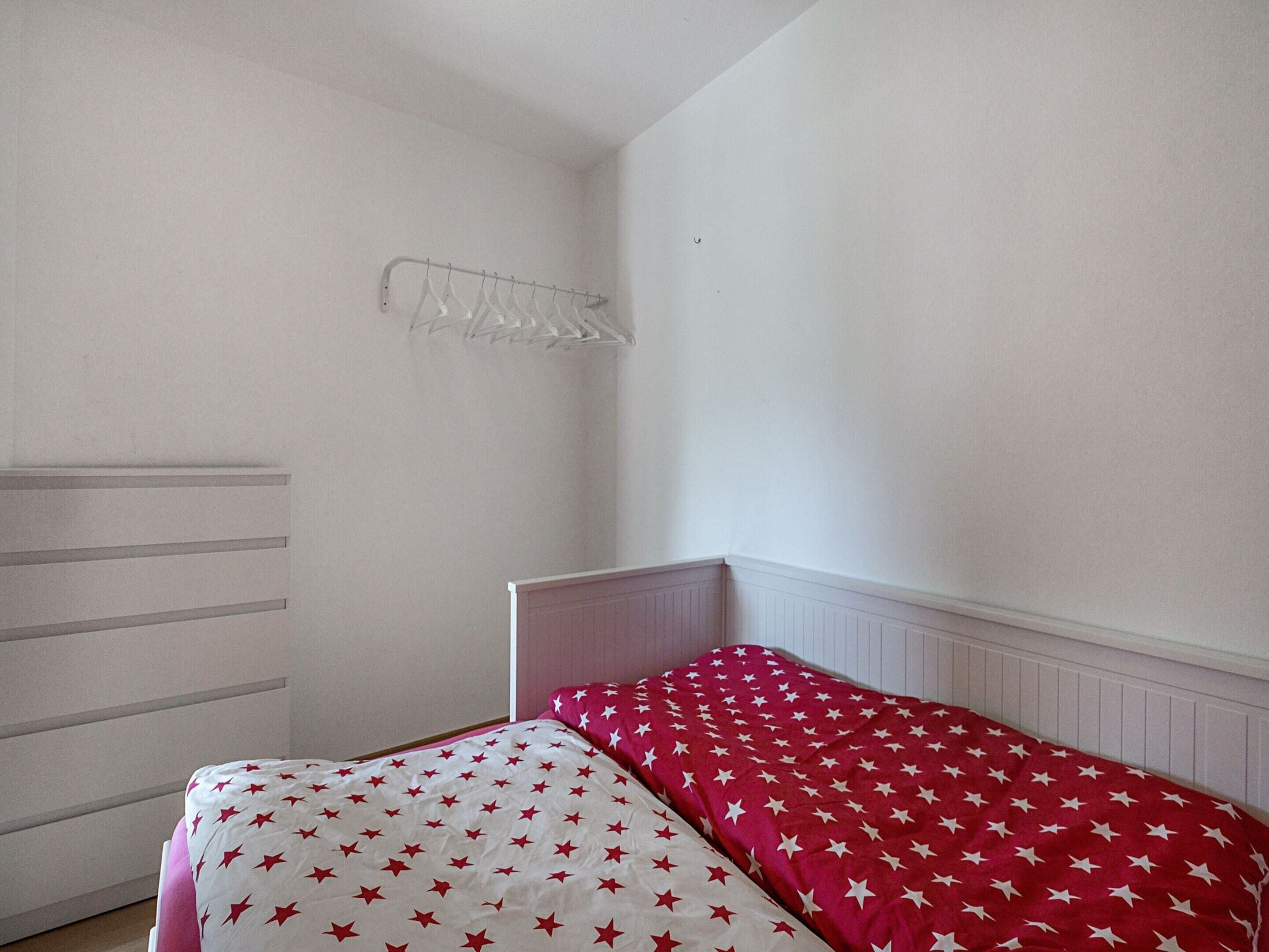 A bedroom with two beds, a radiator, and a white wall.