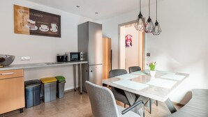 A modern kitchen with a microwave, refrigerator, and a dining area with a table and chairs. - Ferienwohnung im Zentrum von Mahlberg (Mahlberg)